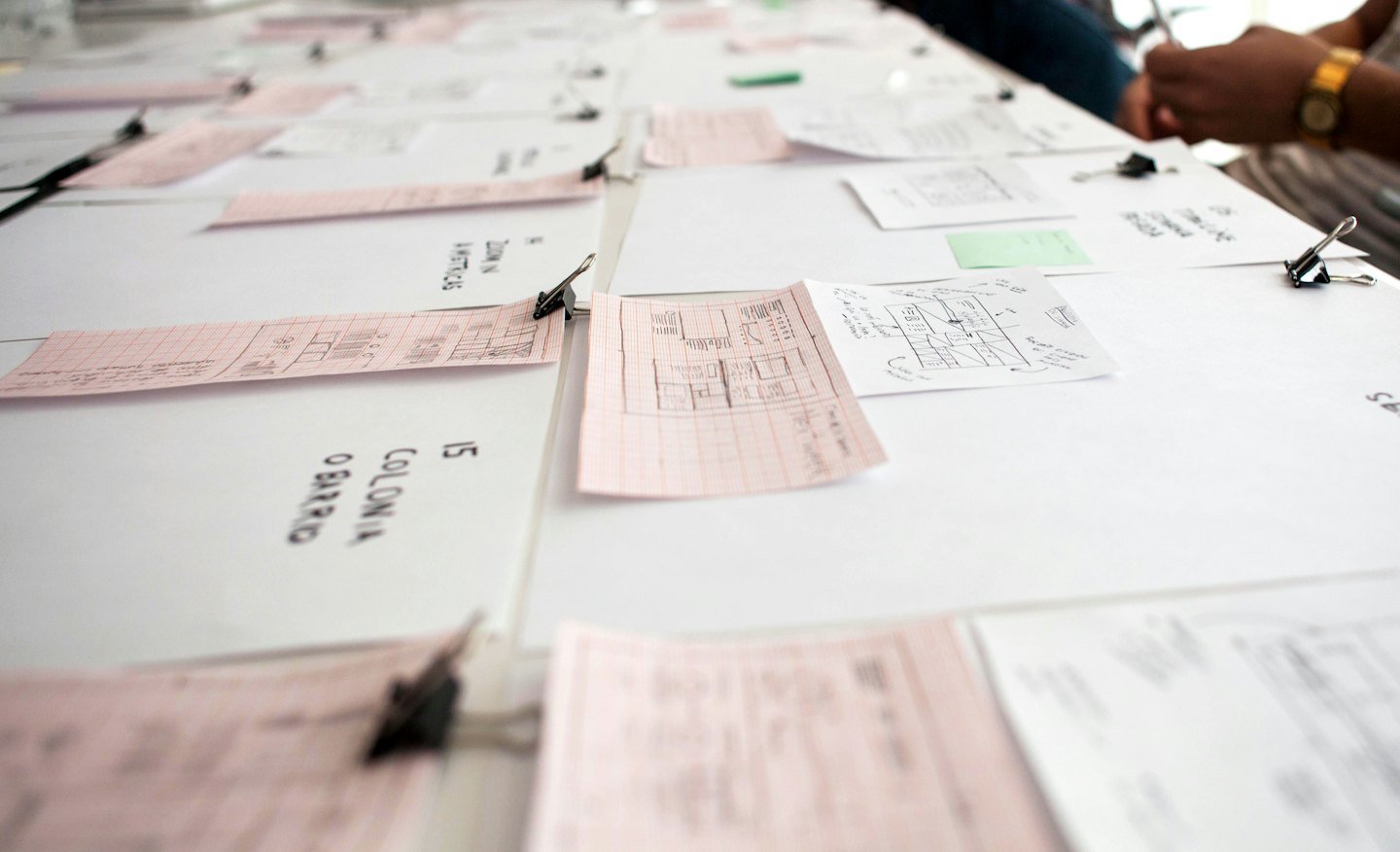 Tisch mit Papieren, Skizzen und handschriftlichen Notizen zur Planung.