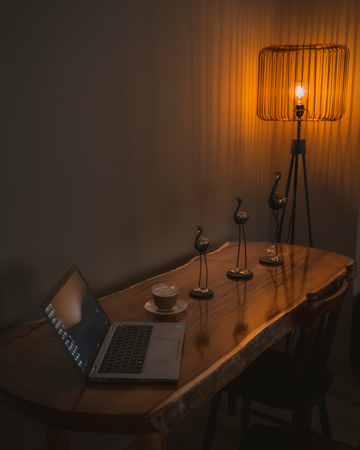 Laptop und Kaffee auf einem Holztisch mit Vogel-Figuren.